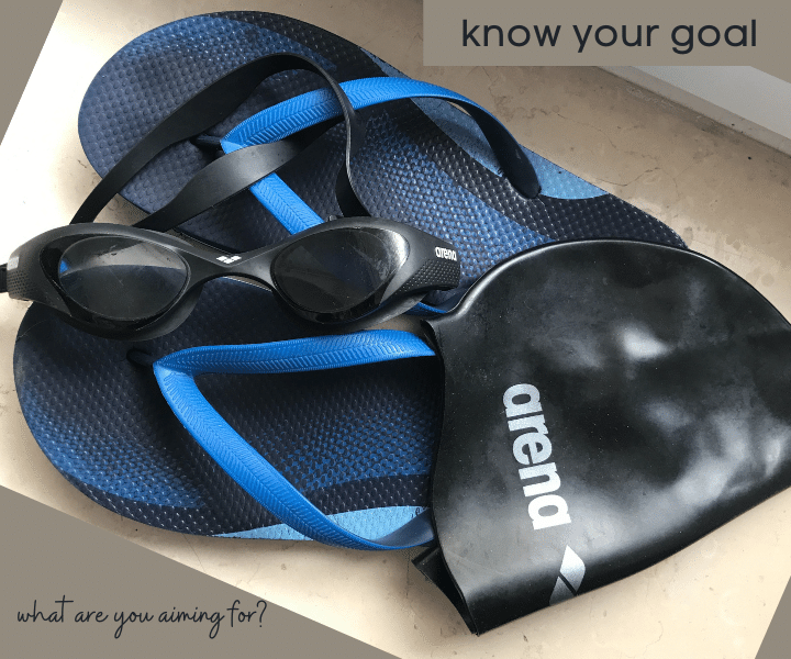 swimming goggles, flip flops and swimming cap piled together